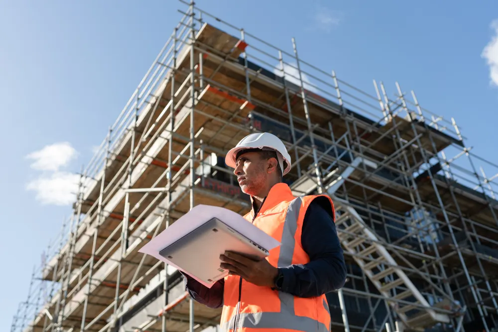 Site engineer reviewing plans at a scaffolded building